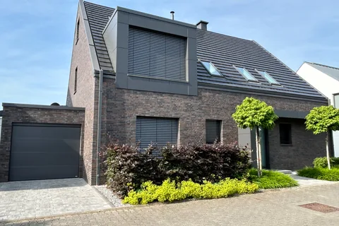 Neu gebautes Wohnhaus mit dunkler Klinkerfassade, Gaube und Garage